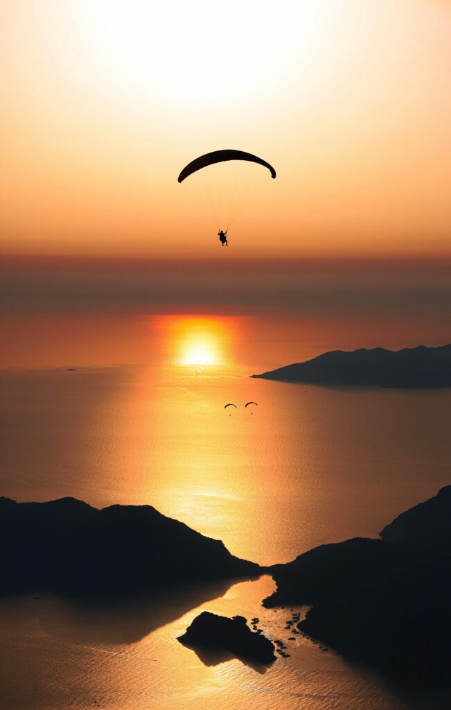 A serene silhouette of a paraglider soaring above the ocean at sunset, capturing the essence of freedom and adventure.